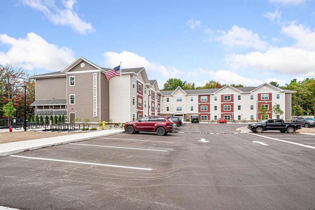 A parking lot in front of a building with a flag on it.
