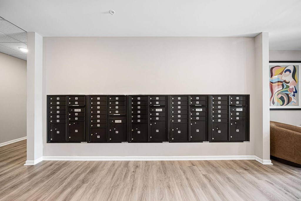 A wall of black filing cabinets in a room with wooden flooring.