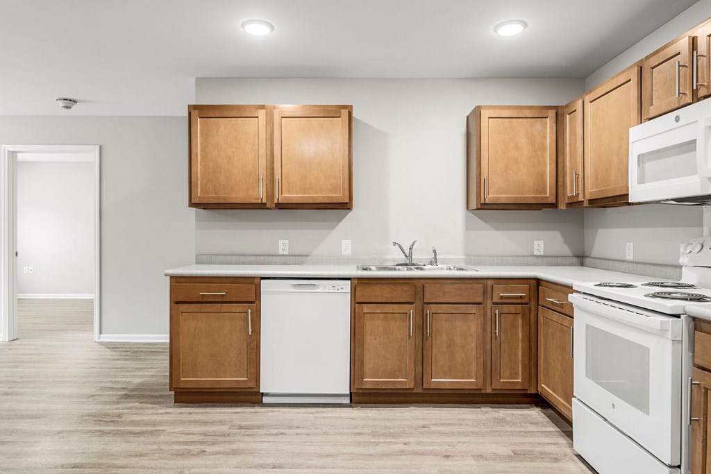 A kitchen with white appliances and wooden cabinets.