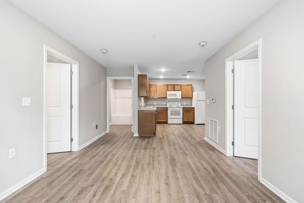 A room with a kitchen area in the background and a box on the floor.