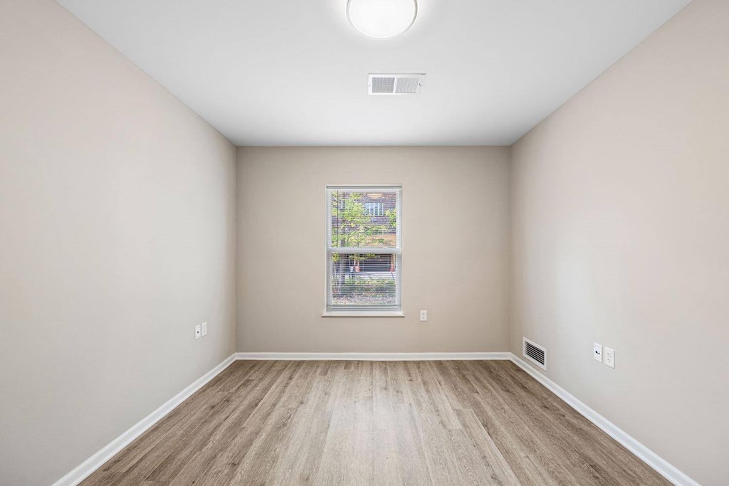 A room with a window and a wooden floor.