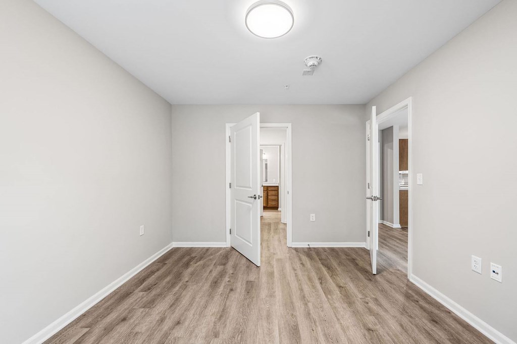 A room with a light on the ceiling and a door open to another room.