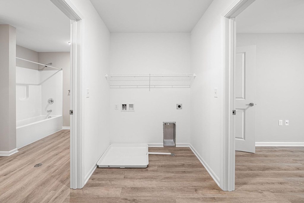 A room with white walls and wooden flooring with a white door on the left and a white door on the right.