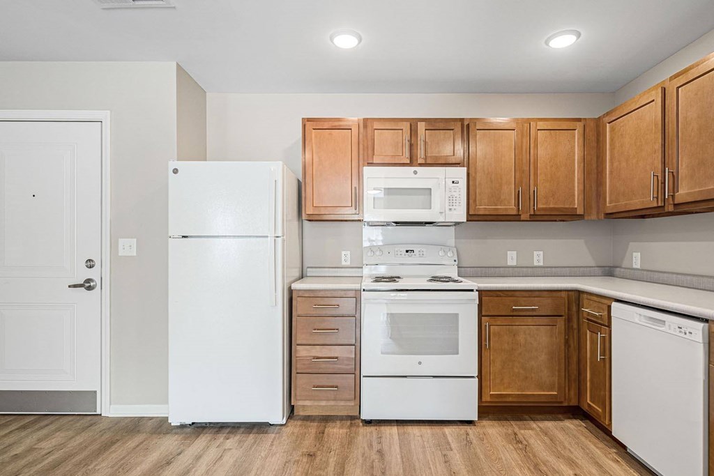 A kitchen with white appliances and wooden cabinets.