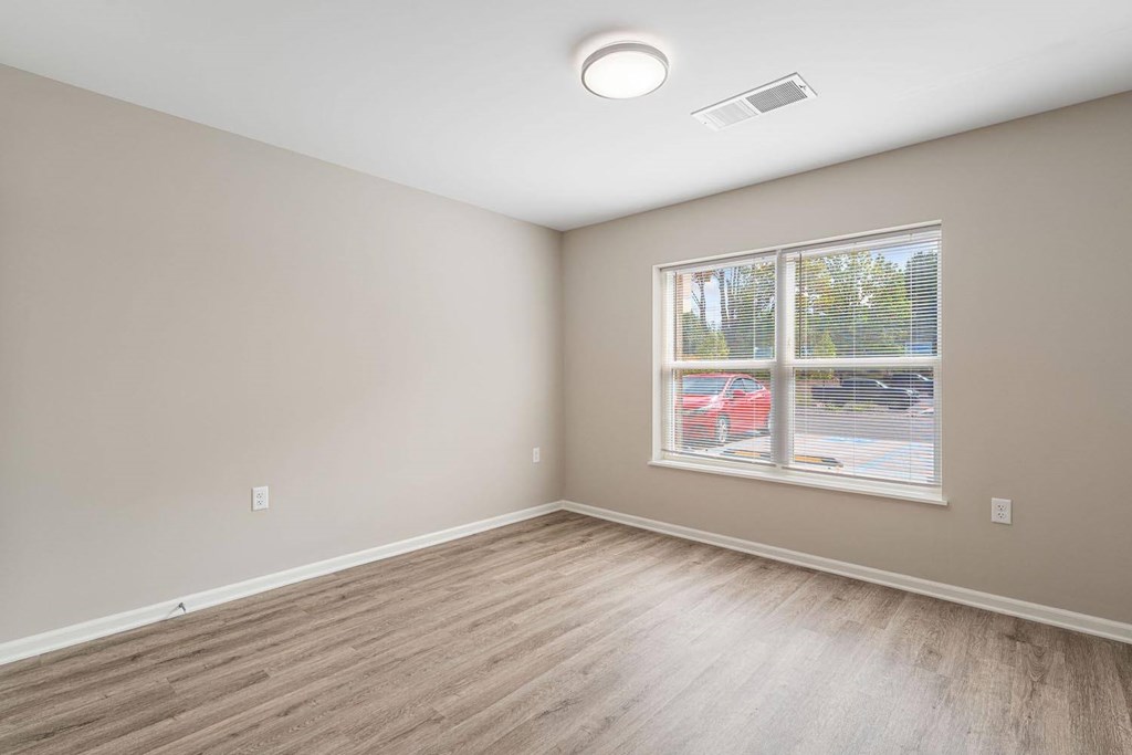 A room with a window showing a red car outside.