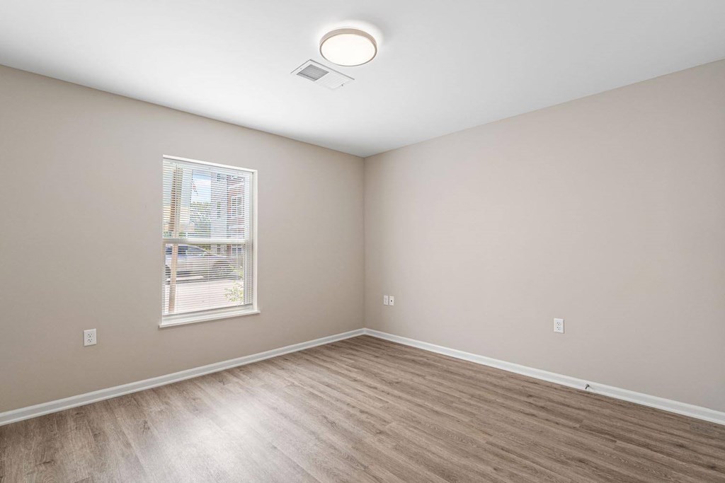A room with a window and a wooden floor.