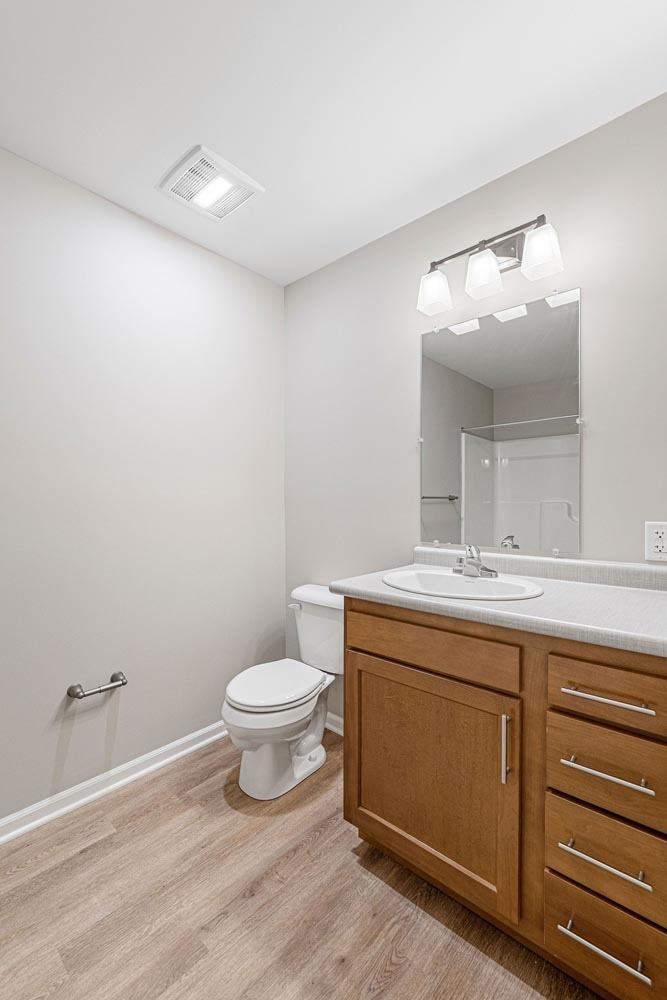 A white toilet sits in a bathroom with a wooden cabinet and a mirror above the sink.