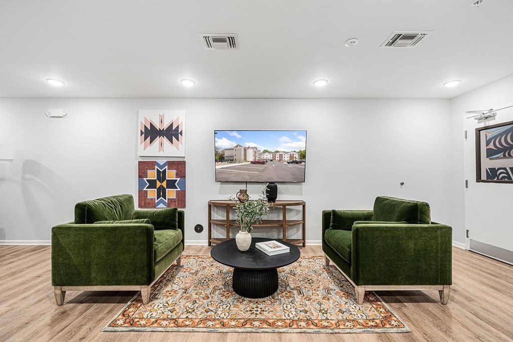 A living room with a green couch, a coffee table, and a painting on the wall.