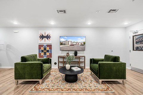A living room with a green couch, a coffee table, and a painting on the wall.
