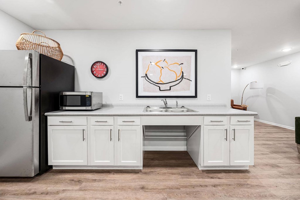 A kitchen with white cabinets and a fridge.