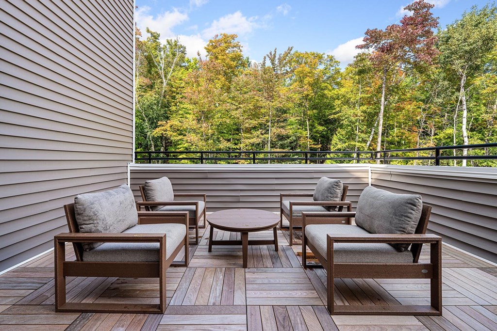 A wooden deck with four chairs and a table.