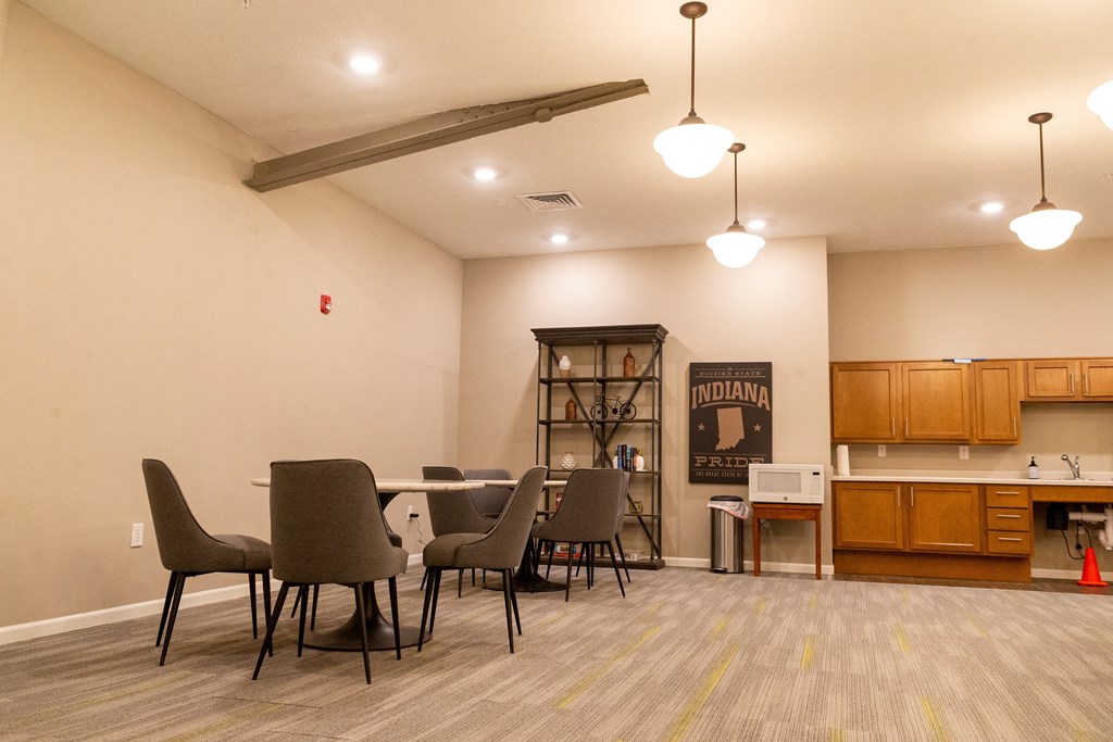 a dining area with a table and chairs and a kitchenette in the background