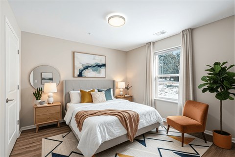 A bedroom with a large bed and a chair.