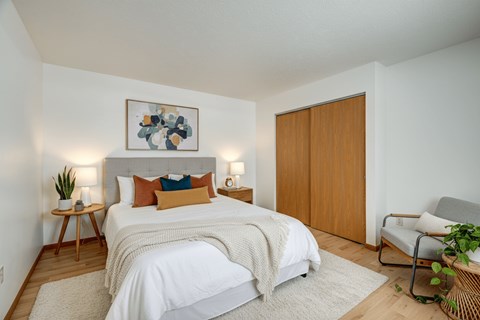 A bedroom with a bed, a chair, and a painting on the wall.