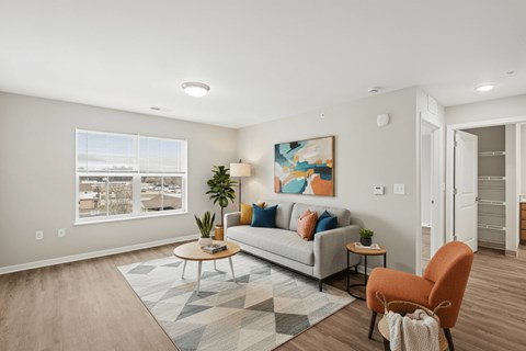 A living room with a grey couch, a coffee table, a painting, a potted plant, and a chair.