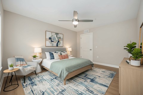 A bedroom with a bed, chair, and rug.