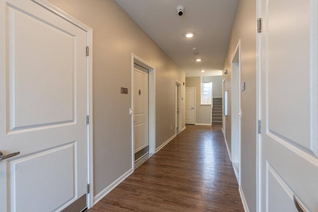 a long hallway with white doors and wood floors