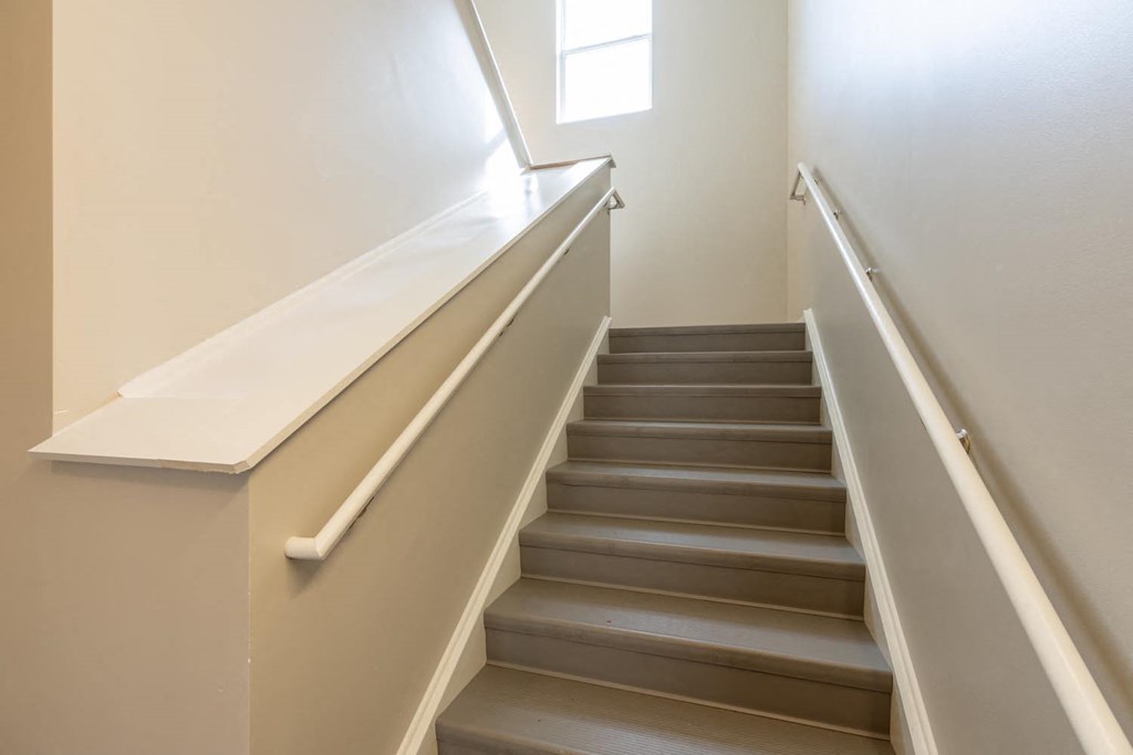a set of stairs with a white railing and a window