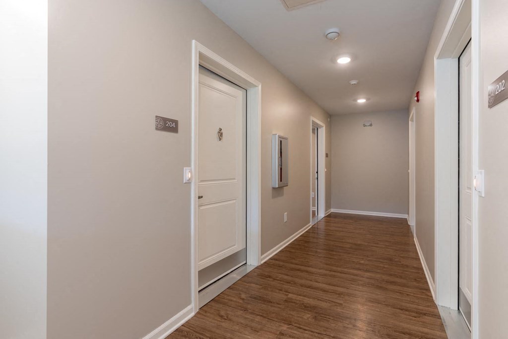 a long hallway with white doors and a wood floor