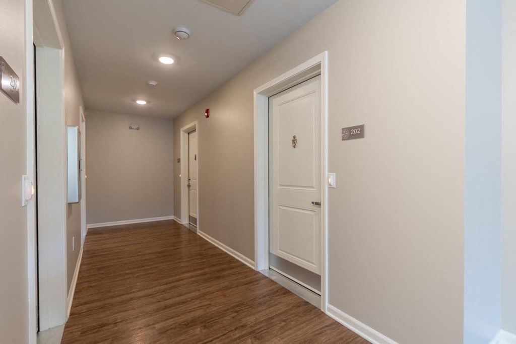 a long hallway with a wood floor and white doors