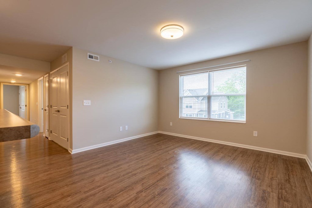 an empty living room with a large window and wooden floors