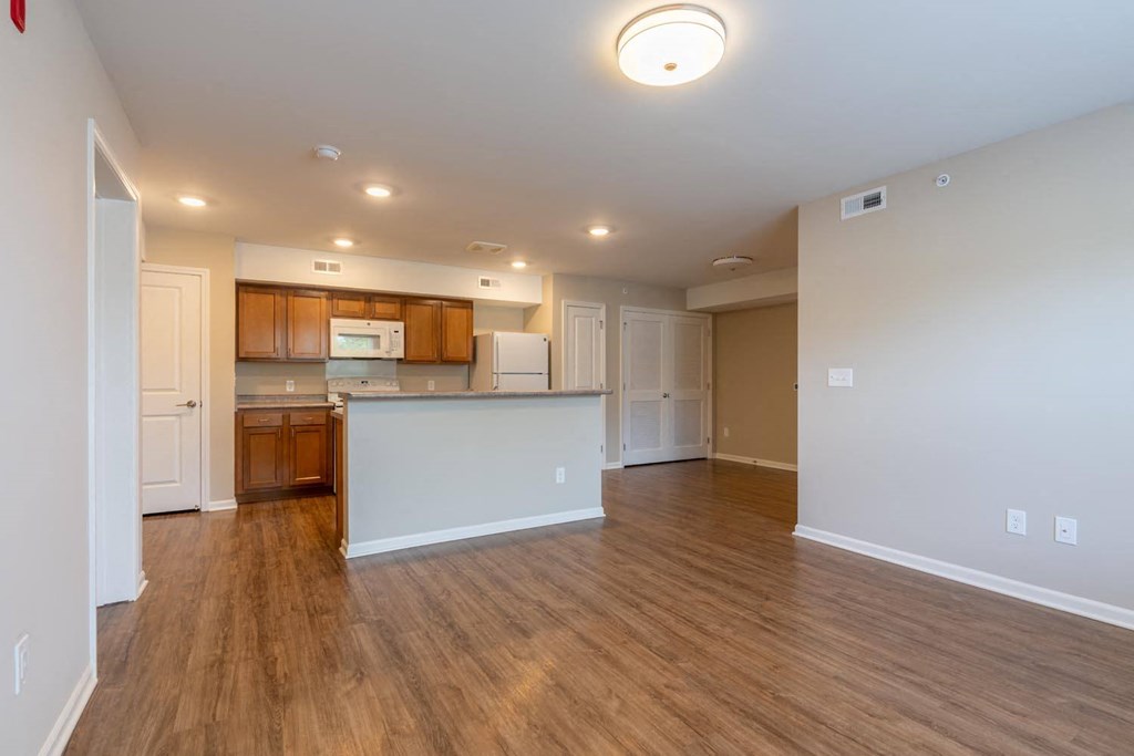 an empty living room and kitchen with wood flooring