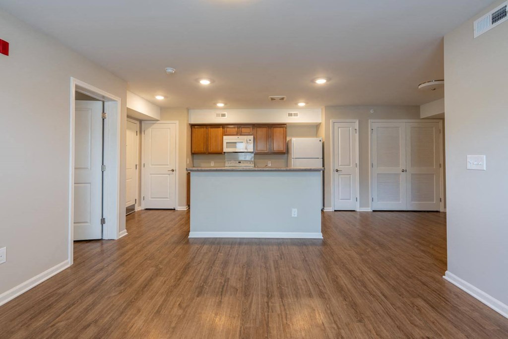 an open kitchen and living room with white cabinets and wood floors