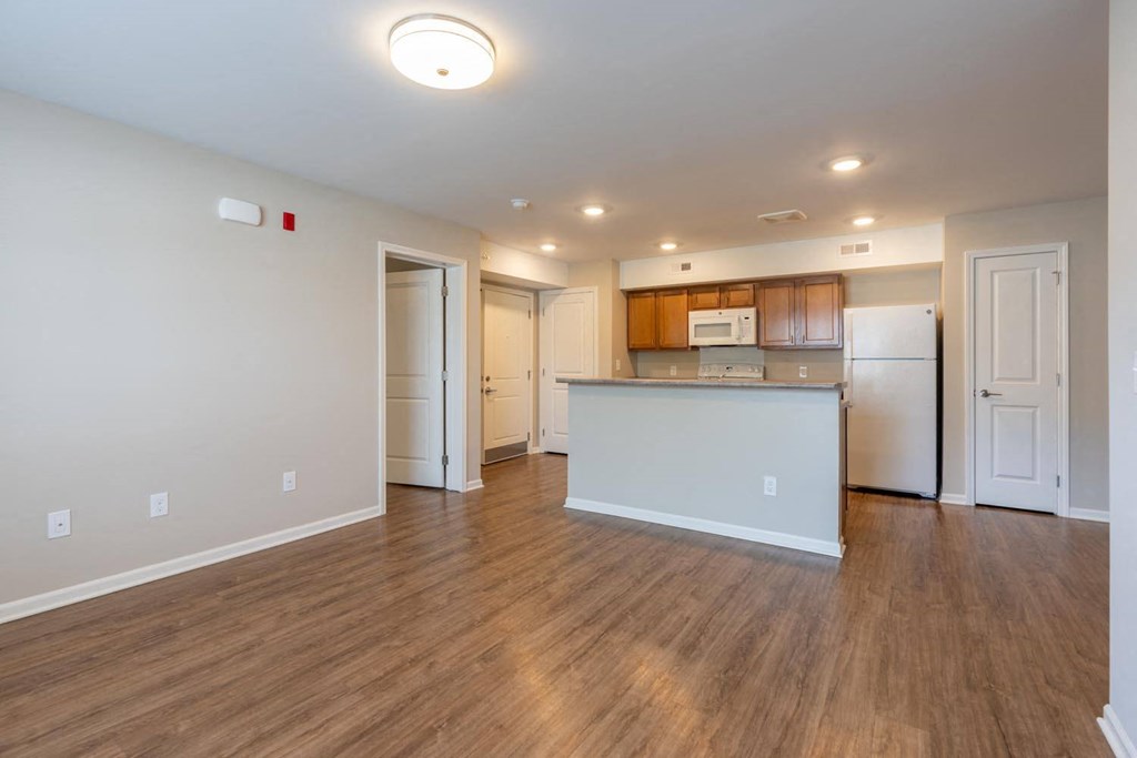 an empty living room and kitchen with a white counter top