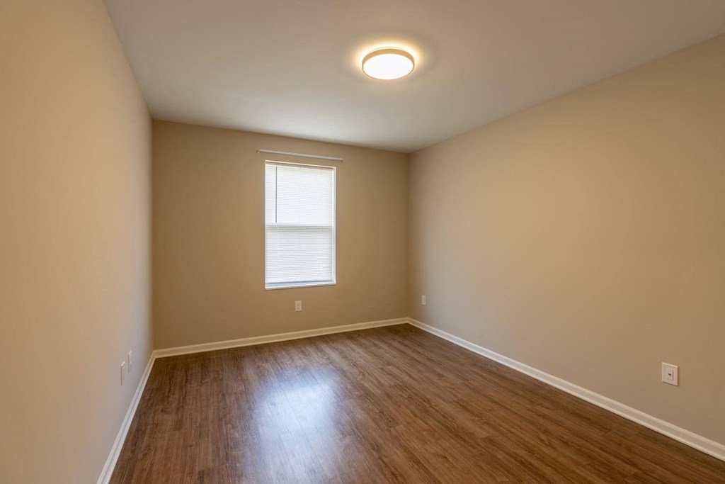 an empty living room with wooden floors and a window