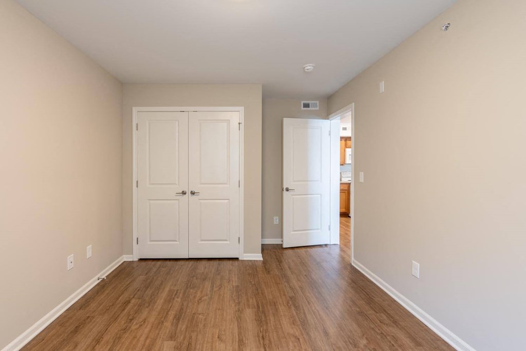 a empty living room with two doors and wood floors