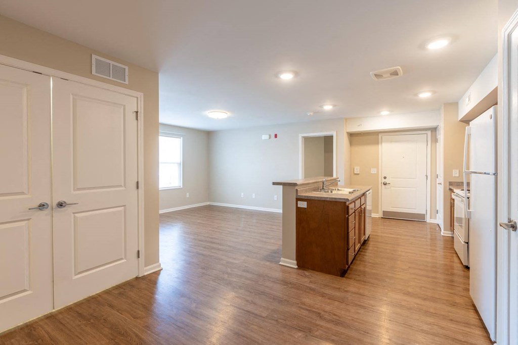 an empty kitchen and living room with wood floors and white doors