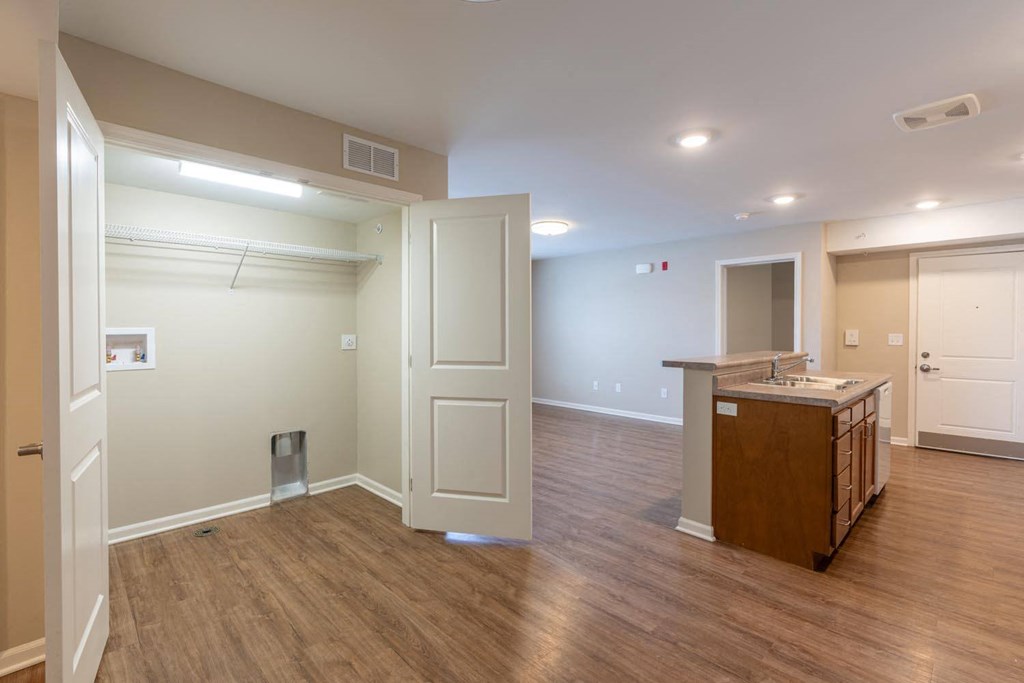 a kitchen and living room with a wooden floor and an open door