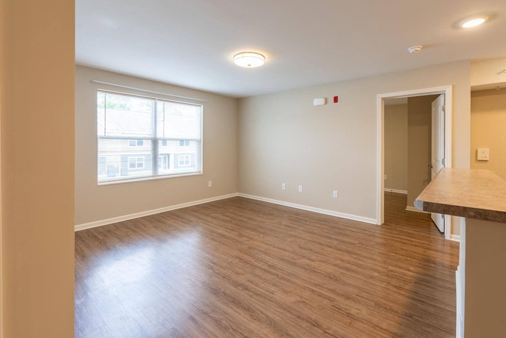 an empty living room with wood floors and a window