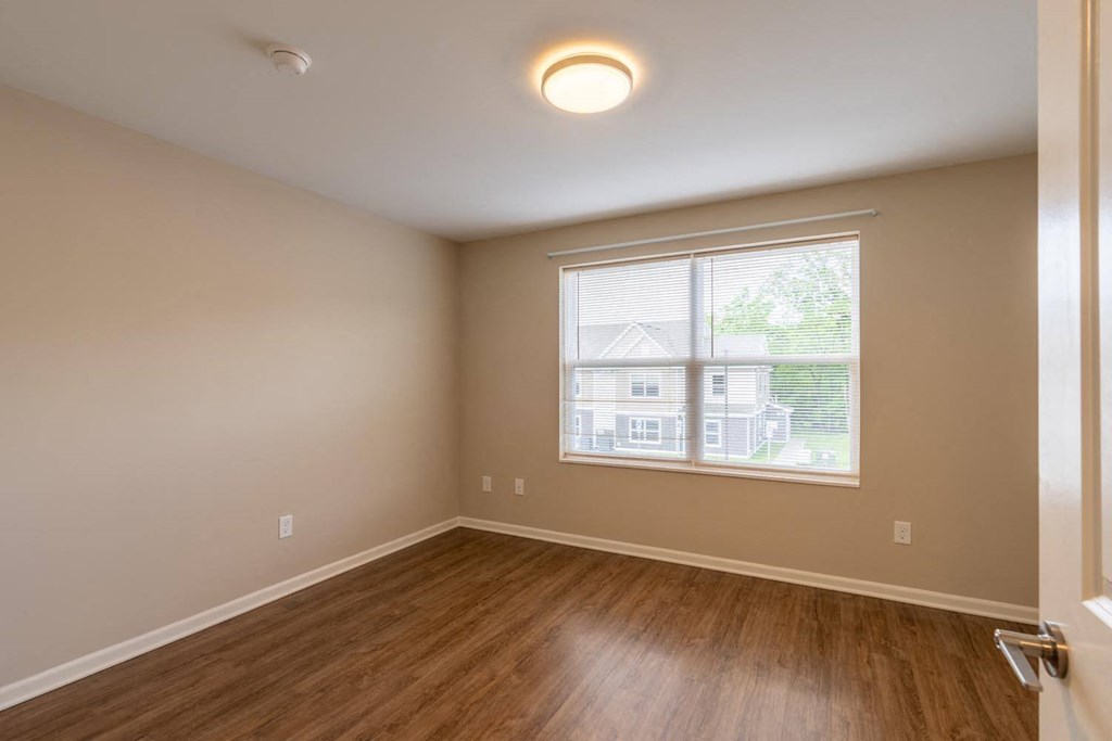 an empty living room with a large window and wooden floors