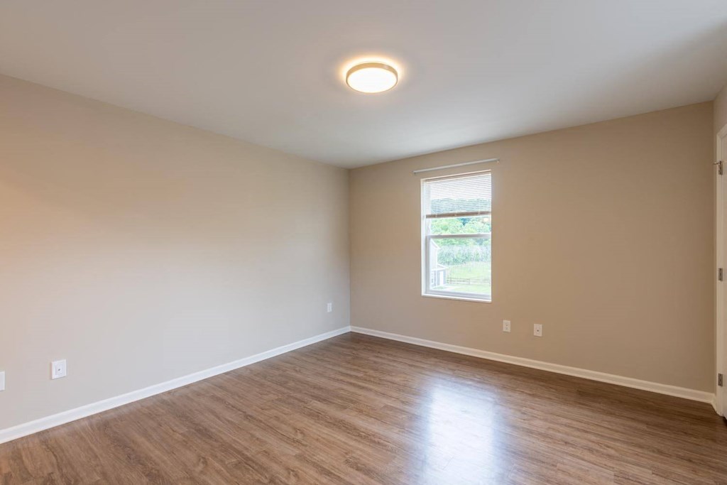 an empty living room with wood floors and a window