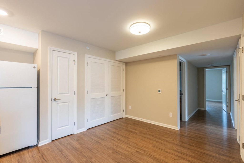 a empty living room with white doors and a refrigerator