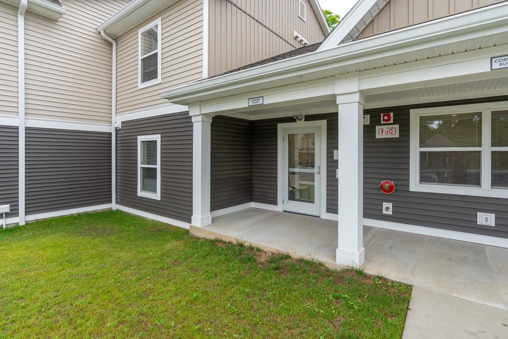 the front entrance of a house with a porch and a lawn