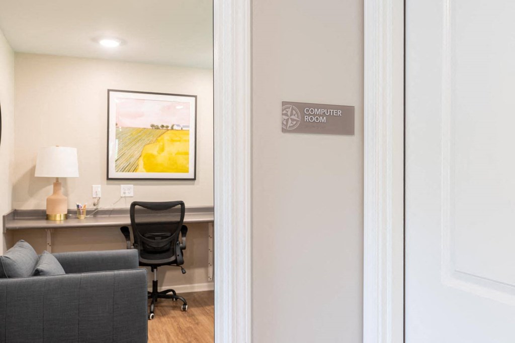 a door leading into an office with a desk and a chair