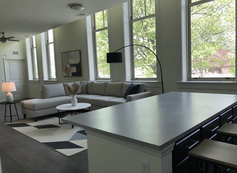 A modern living room with a grey sofa and a large window.