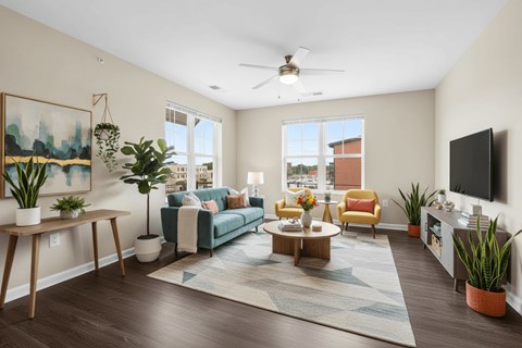 A living room with a blue couch and a painting on the wall.