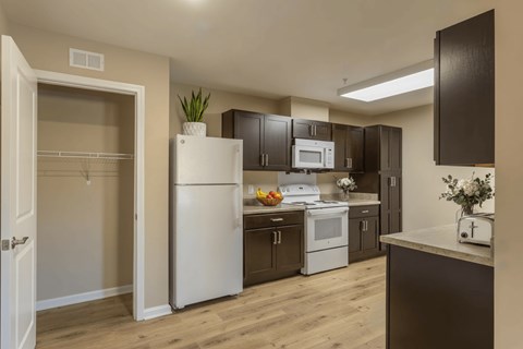 A kitchen with a white refrigerator and brown cabinets.