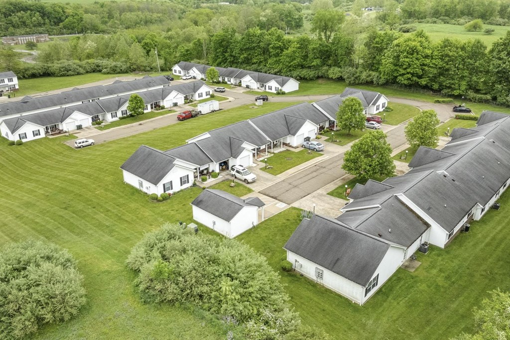 an aerial view of a group of white houses in a field