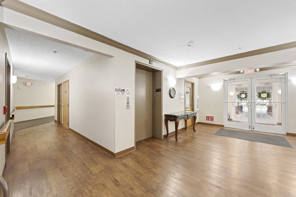 the lobby of a building with a wood floor and white walls