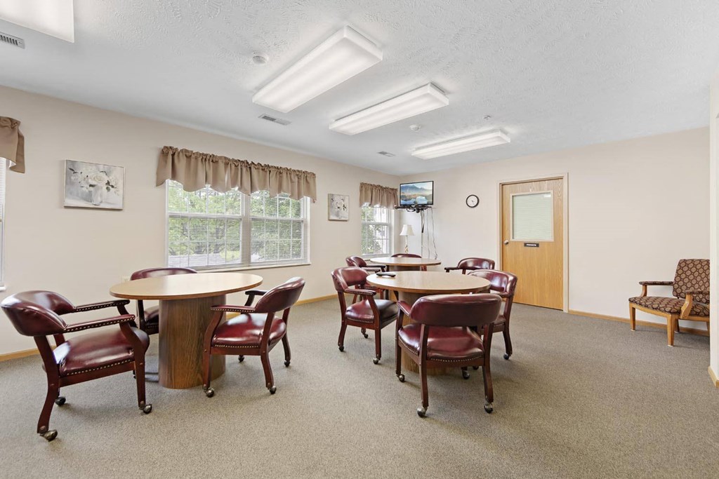 a community room with tables and chairs and a television