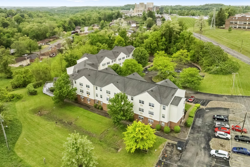 an aerial view of a white house with a gray roof and a neighborhood with trees