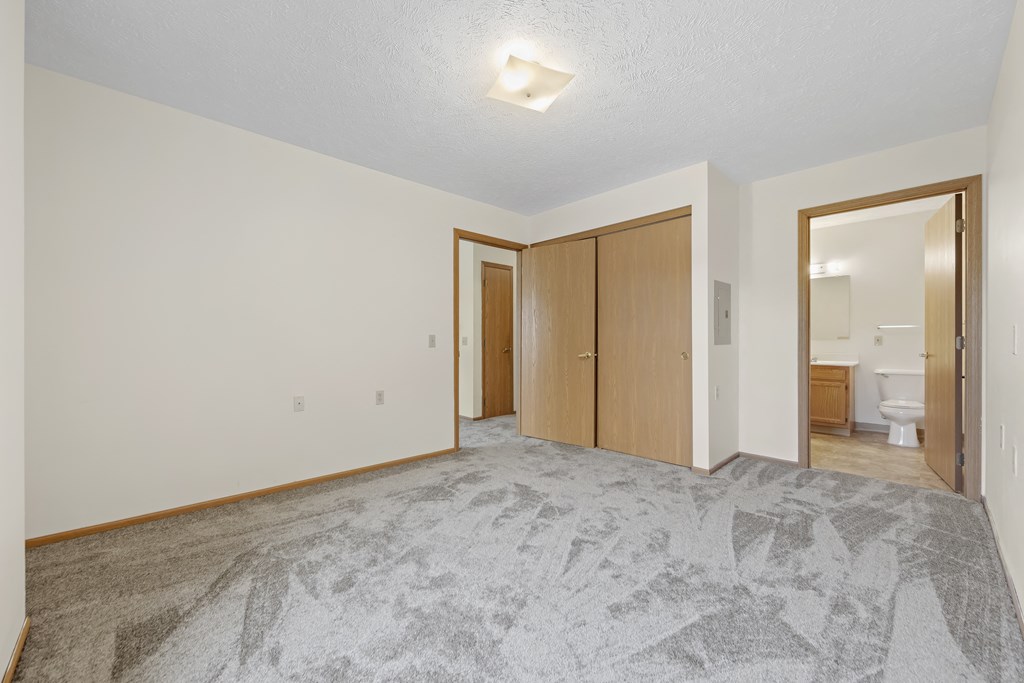 an empty living room with a door to a bathroom and a closet
