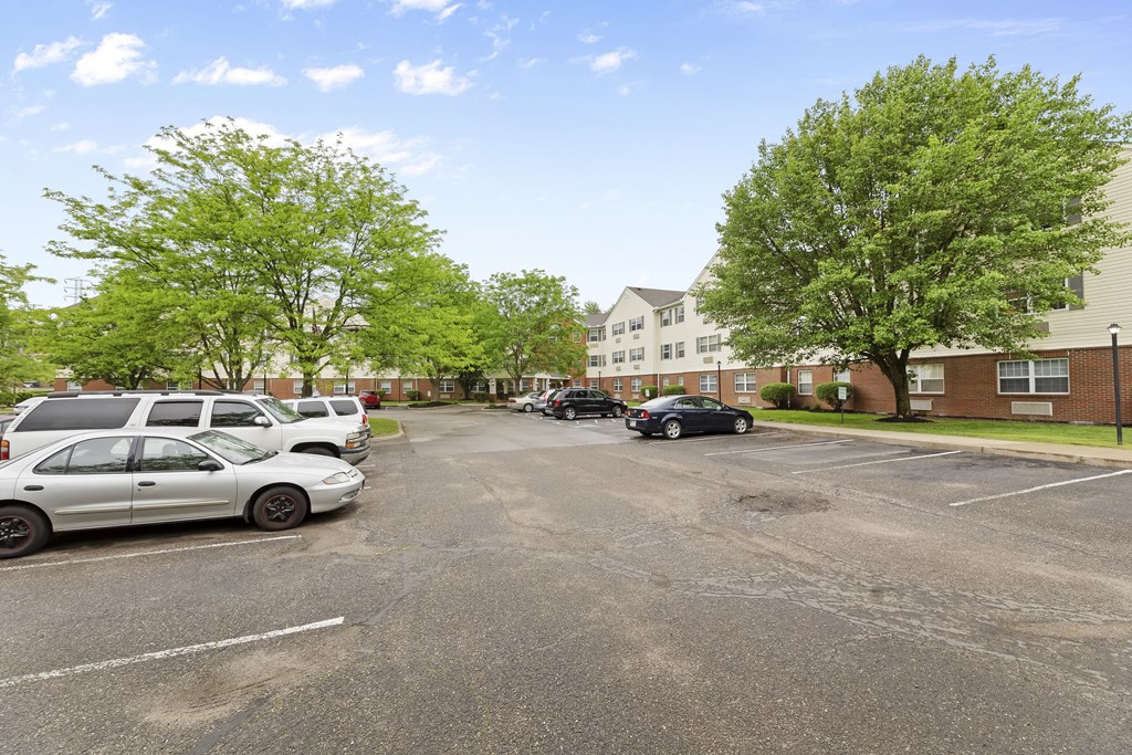 an empty parking lot with cars in front of apartment buildings