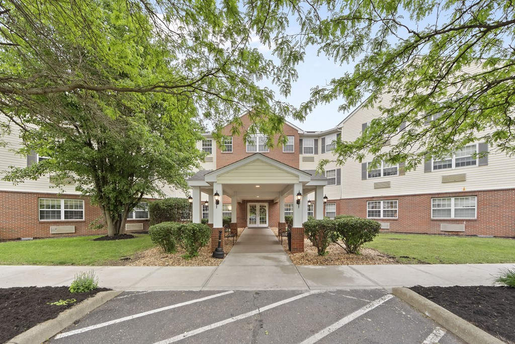 the entrance to a brick apartment building with trees and a sidewalk
