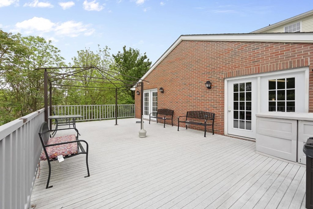 a white deck with benches and a brick building