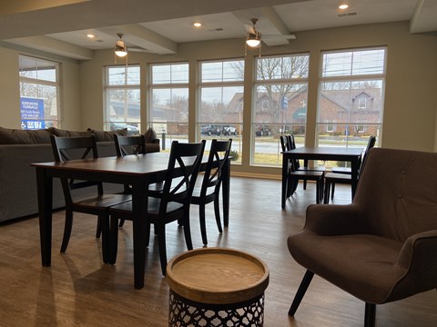 a large living room with tables and chairs and large windows
